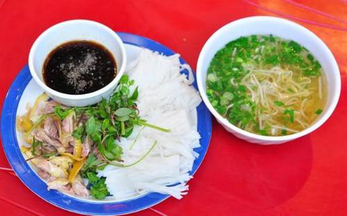 Phở chấm Phở chấm là biến tấu mới lạ của món phở truyền thống, bao gồm thịt gà đùi xé, lá chanh thái chỉ rắc lên trên. Phở để nguyên bánh, không chần, cắt thành từng khúc ngắn khoảng 5 cm, xếp gọn gàng trên đĩa. Khi khách gọi, nhân viên phục vụ sẽ mang ra cùng một bát xì dầu nhỏ, kèm theo đĩa ớt tươi và vài lát chanh. Phở chấm được bán ở phố Bà Triệu với giá từ 30.000 đồng một phần. Ảnh: Lozi.vn.