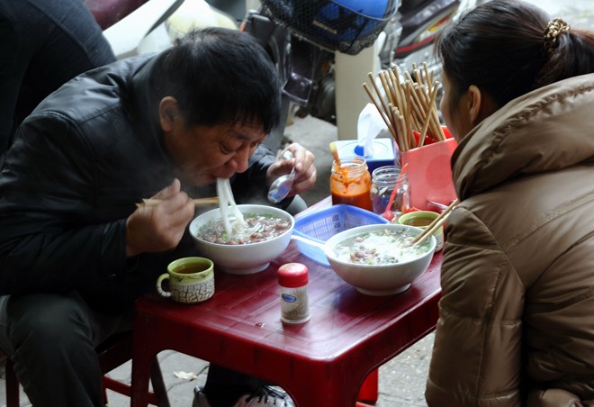 Xì xụp phở sáng: Thưởng thức phở trong bữa sáng ngày lạnh là thói quen của không ít người. Đặc biệt, giữa trời mưa rét được húp một bát phở nóng hổi, ăn từng miếng đậm đà và xuýt xoa là một điều khiến nhiều người nhớ mãi khi rời xa Hà Nội. Ảnh: AFP-JIJI.