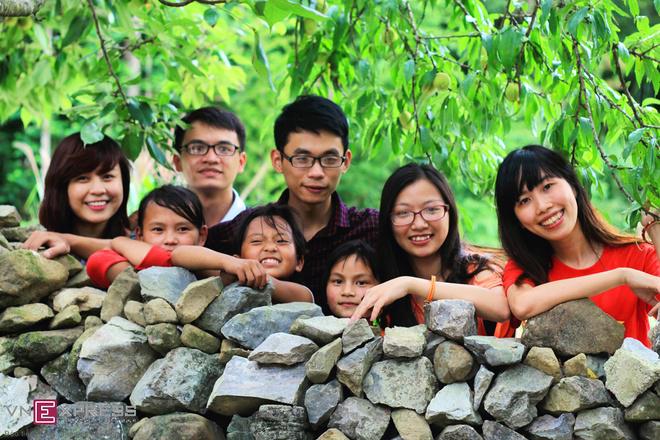 Những đứa trẻ vui đùa cùng du khách bên bờ rào đá, dưới những tán đào mùa trổ quả.