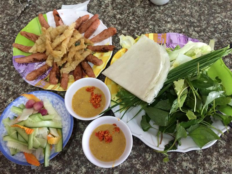 Nem cuốn với bánh tráng, rau sống, dưa chua và bánh tráng chiên giòn, chấm nước tương đậu phụng...