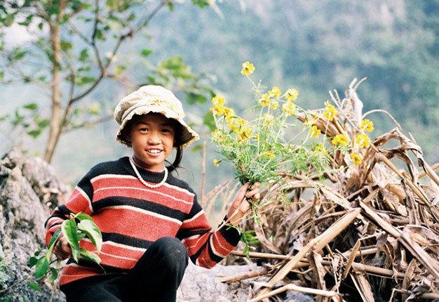 Bé làm duyên với hoa cúc cam - Ảnh: Thủy Trần