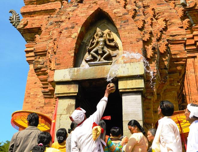 Dùng lọ nước thánh tưới lên tượng thần. Ảnh: Văn Trãi