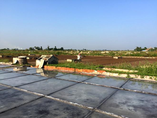 . Nước chạt nồng độ cao được rải trên mặt sân ximăng, nhờ nắng bốc hơi nước và dần kết tinh thành muối. Ảnh: Băng Giang.