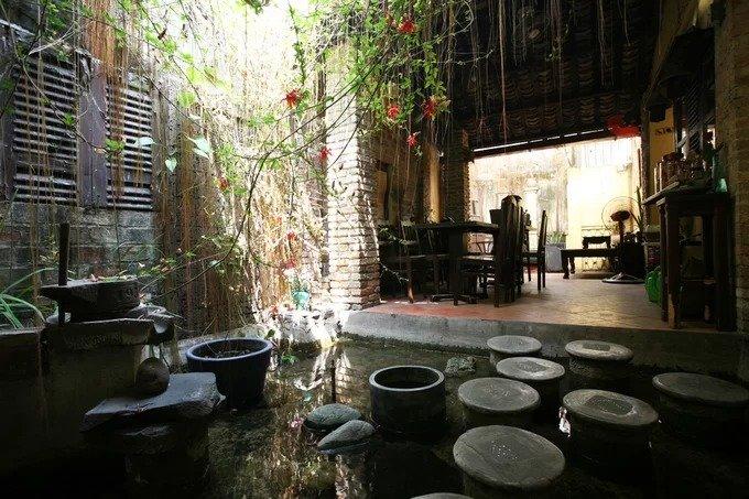 Phía sau gian nhà bên trái có một khoảng sân trời, nối liền với không gian cà phê phía sau. Để đi tới chỗ này phải bước trên những bậc đá trên mặt nước.