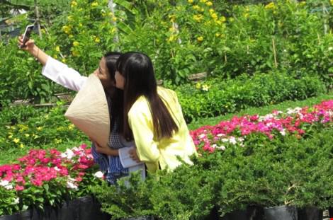 Hai cô gái trong trang phục áo bà ba và nón lá đến làng hoa để cùng "tự sướng" với hoa. Ảnh: N.NAM