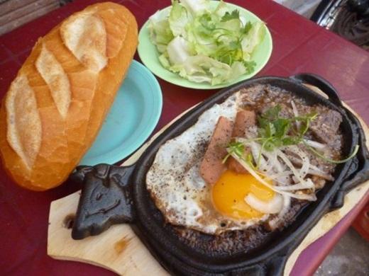 Nếu chỉ muốn một món ăn đơn giản, an toàn cho buổi tối yên bình thì bò né ắt hẳn sẽ làm bạn hài lòng. Thịt bò mềm, pa tê thơm lừng, trứng ốp la lòng đào cùng một ít phô mai, xé từng mẩu bánh mì nóng ăn kèm, bữa tối cùng bò né sẽ làm bạn ấm bụng hơn bao giờ hết. (Ảnh: Internet)